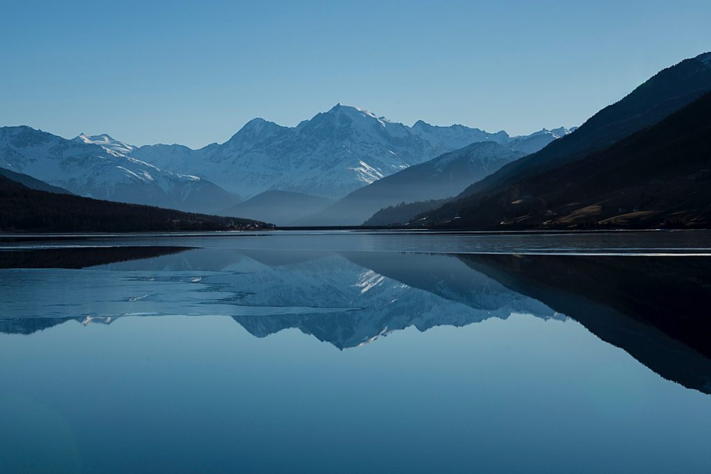 A peaceful lake with still water and mountations beyond, suggesting the stillness of mind one can achieve after doing a creative practice