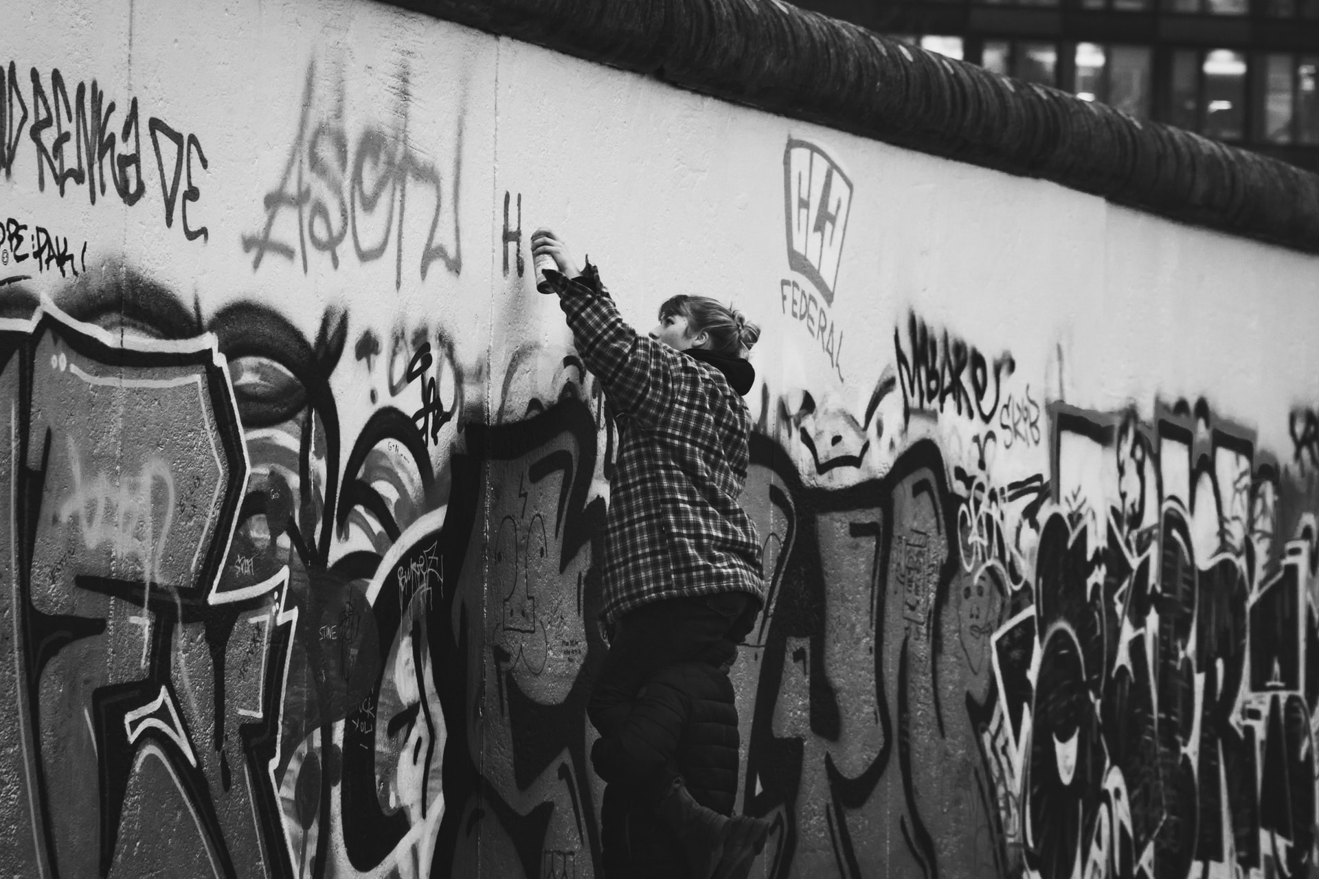 An artist spray painting on a building, suggesting the idea of the Artist as Pioneer of Culture.